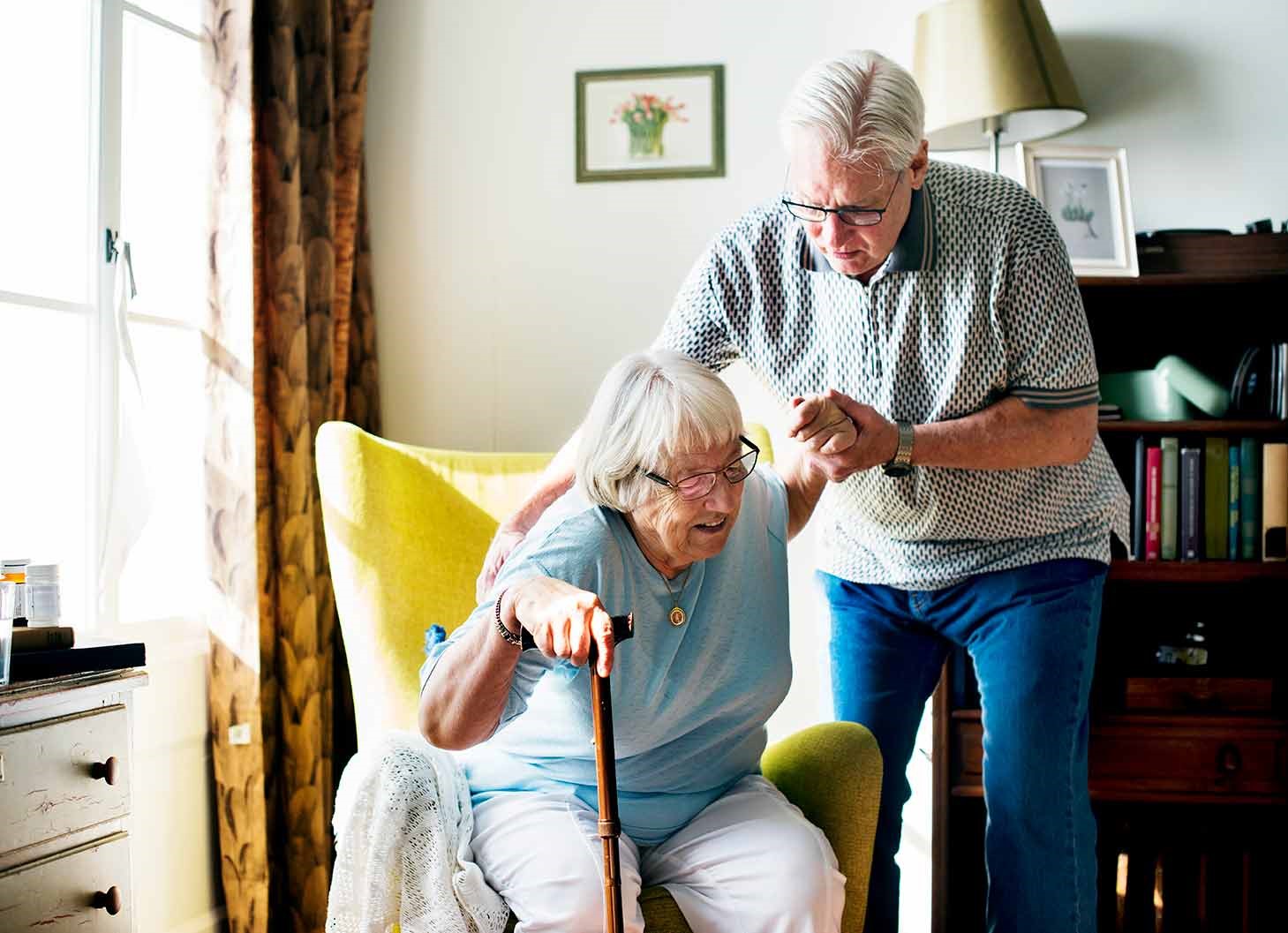 helping an elderly woman to get up from couch