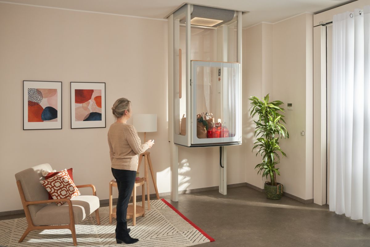 Woman in her living room, lifting the Uplifts S2 with her groceries inside.